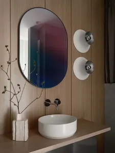 Modern bathroom interior with a wooden accent wall, a sleek white sink, and a round mirror.