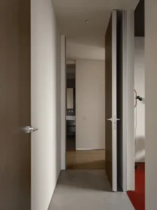 Interior shot of a modern residential entryway featuring concrete flooring and wooden doors.