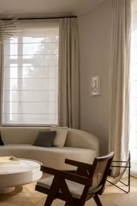 Modern interior design featuring a circular couch and white curtains.