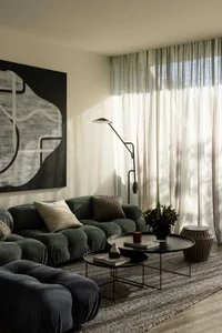 Modern living room interior with plush fabric sofa, glass coffee table, and metallic accents.