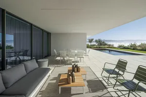 A minimalist outdoor lounge with metal furniture and a pool view.