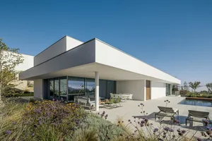 A modern residential building with a concrete exterior and large glass windows.