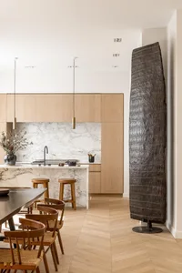 A modern residential kitchen with minimalist design, featuring wooden furniture, marble countertops, and a white marble backs