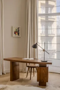 A modern study area featuring a wooden table, a simple stool, and a contemporary lamp.