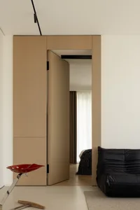 A minimalist bedroom featuring natural wood elements and a black leather sofa.
