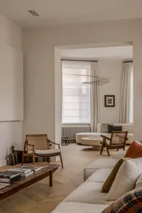 A modern living room featuring wooden materials and furniture, with a neutral color palette and natural light streaming in fr