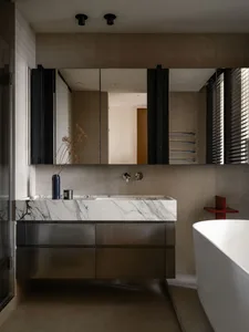 Modern bathroom featuring a marble countertop sink with stainless steel cabinets and a minimalist vanity.