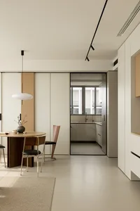 A modern minimalist kitchen with white laminate cabinets and a white pendant light fixture.