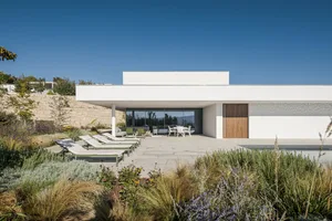 Exterior view of a modern residential building featuring concrete, glass, and wooden elements.