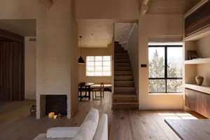 A minimalist indoor space featuring wooden stairs, brick walls, and concrete details.