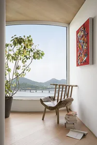 A minimalist living room featuring a wooden window overlooking distant mountains and a bridge.
