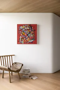 簡約室內設計，展現一件紅色抽象藝術作品、一張木椅，以及一疊書籍置於淺色木地板上