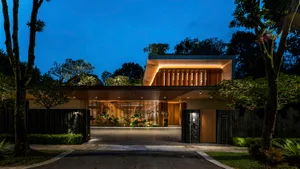 Modern entrance with wooden panels of a residential house at dusk, featuring warm lighting and lush greenery.