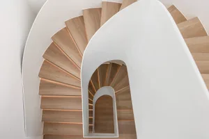 Modern staircase with wooden steps and white walls.