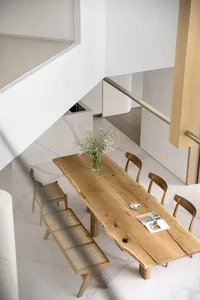 Modern dining room featuring a rustic oak dining table with chairs and a bench, a vase of baby's breath flowers, and a book a