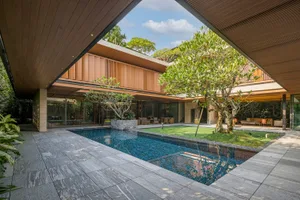 A modern minimalist residential courtyard with a pool, featuring stone, glass, and wood materials.