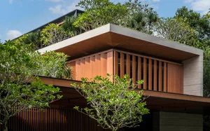 A modern residential building with wood and concrete exterior features a green, rooftop garden.