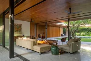 A modern living room with wooden elements and a large window overlooking a green outdoor space.