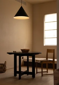 Minimalist interior design featuring a simple wooden table with a bowl on top, a wooden chair, and a window letting in natura