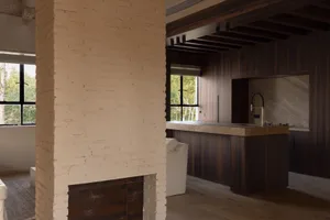 Modern, minimalist kitchen with wooden cabinets and a brick wall.