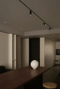 Modern minimalist dining room with a wooden table and white vase.