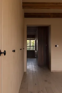 A modern minimalist interior with wooden flooring, concrete walls, and large windows.