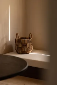 A woven basket on a cushioned bench, with sunlight streaming through a window.