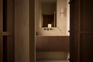 A minimalist bathroom with a wooden vanity and ceramic sink.