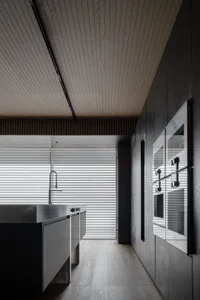A modern residential kitchen features concrete countertops, wooden cabinets, and metal appliances.