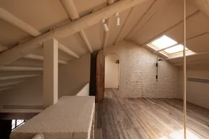 Modern attic space with wooden flooring, brick walls, and plaster beams