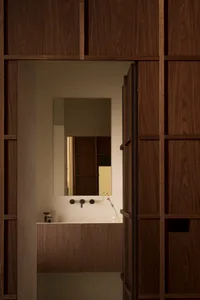 Modern bathroom with dark wooden walls and a white sink area.