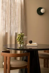 Modern dining room featuring a black glass table with blackwood legs and a leather upholstered bench, complemented by a minim