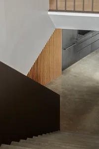 A modern kitchen with wooden paneling and dark concrete flooring.