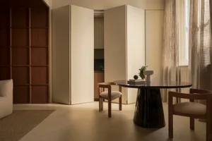 A minimalist apartment interior with modern furniture, wooden accents, and a glass table.