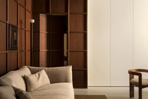 Modern minimalist living room with wooden paneled walls and a beige upholstered sofa.