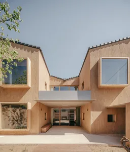 A modern building facade made of clay with large windows and a concrete awning.