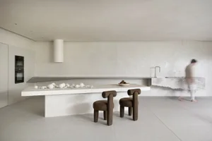 A minimalist kitchen with a concrete island and chair.