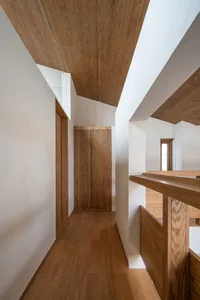 Modern minimalist wooden interior design featuring a corridor with hardwood flooring and wooden paneling.