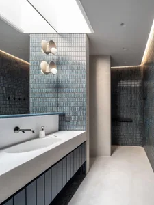Modern bathroom featuring a concrete floor and walls with blue glass mosaic tiles.