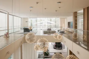 A modern living room with metallic chandeliers and glass windows.