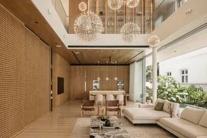 A spacious modern living room with wooden elements, featuring minimalist furniture and large windows.