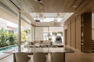 A modern living room featuring wooden furniture, glass walls, and a large sofa.