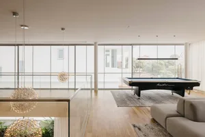 Modern interior design featuring contemporary metallic lighting fixtures and a sleek glass-couch in a spacious living area.