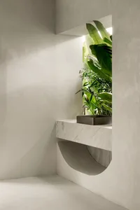 A minimalist concrete interior space featuring a sleek floating sink and lush green plants.