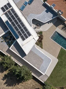 Modern private residence with concrete rooftop featuring solar panels and a geometric outdoor space.