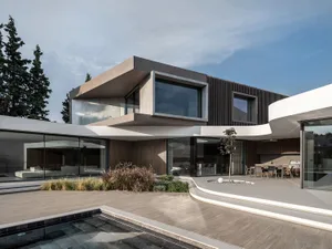 A modern residential exterior featuring concrete, glass, and wooden materials.
