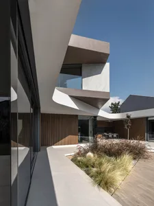 Modern residential exterior featuring glass walls and concrete structure.