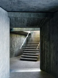 A modern, minimalist staircase with concrete steps and walls.