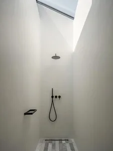 A minimalist bathroom featuring a concrete shower area with a skylight.