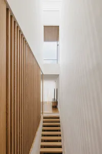 Modern interior design with minimalist white space featuring wood elements and a high window.